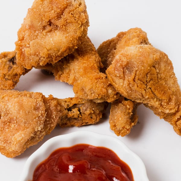 Crispy fried chicken wings from DMac & Wings, with a side of ketchup on a white background.